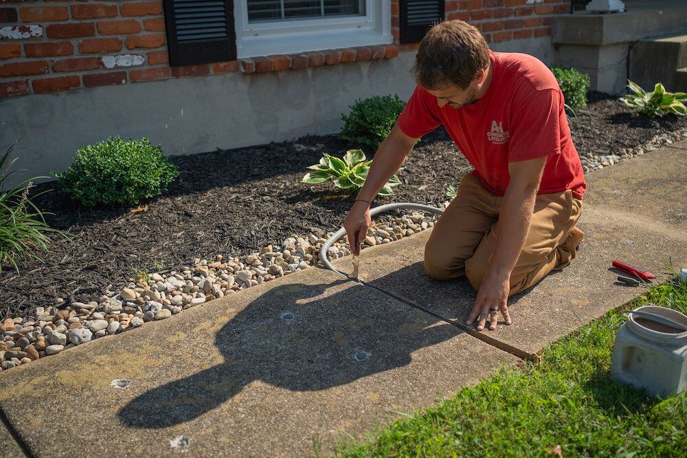A cracked sidewalk with a person stepping over it, highlighting the need for repair